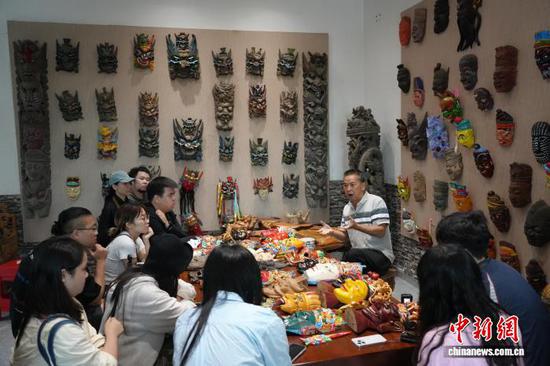 图为安顺木雕非遗代表性传承人秦发忠(中)为游客讲解傩戏面具。石小杰 摄 图为安顺木雕非遗代表性传承人秦发忠(中)为游客讲解傩戏面具。石小杰 摄