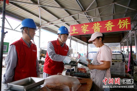图为国网天津武清公司工作人员在东马圈集贸市场向商贩推广“扫码用电”服务。冯克旭 摄