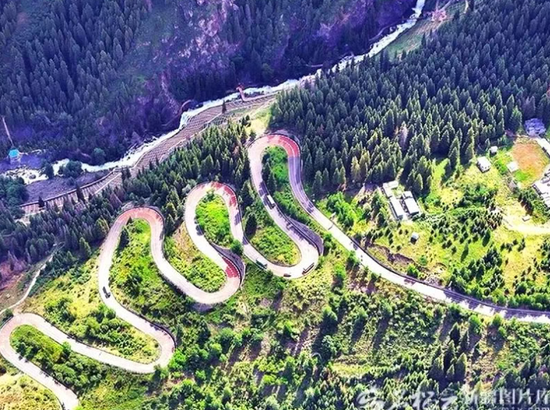 天山天池的九曲十八弯盘山公路——从空中俯瞰，一条白色公路如丝带般蜿蜒盘旋于博格达峰脚下的雪岭云杉林中，九曲十八弯，层层叠叠，在墨绿色的林海间划出优美的曲线。公路依山势而建，从山脚一路攀升至天山天池湖畔，两侧雪岭云杉如塔如伞，密密匝匝，将公路拥入绿色的怀抱。刘跃摄