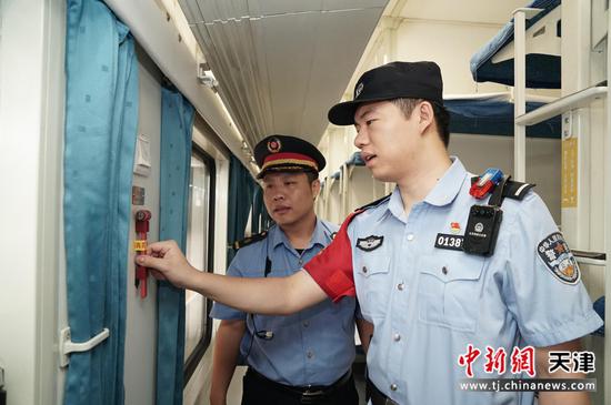 图为北京铁路公安局天津公安处乘警支队民警正在车厢内检查安全设施，确保列车平稳运行。（北京铁路公安局天津公安处供图）