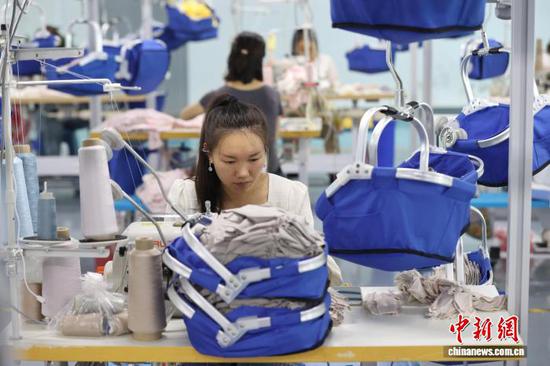10月14日，在贵州省都匀市绿茵湖轻纺产业园内，多家服装企业依托智能吊挂、数据管控等数字化设备组织生产。中新社记者 瞿宏伦 摄
