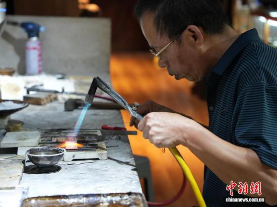 10月19日，贵州省雷山县西江镇麻料村，村里的银匠师在制作苗族银饰。中新社记者 周燕玲 摄