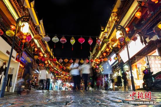图为10月14日，贵州都匀石板街，古朴街巷交织民俗风情与市井烟火吸引游客前来逛街游玩。中新社记者 张畅 摄
