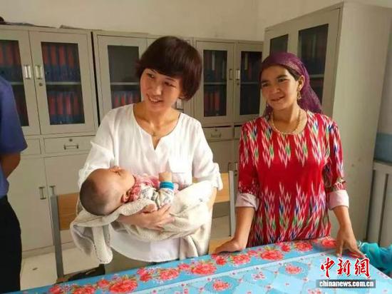 图为芦玉香抱着刚出生4个月的“小石榴”。（天津市西青区委统战部供图）