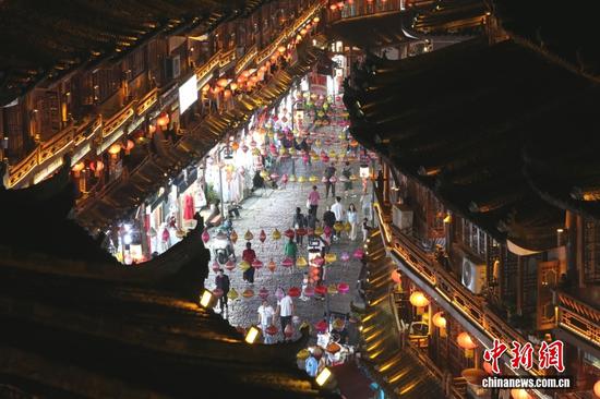 图为10月14日，夜幕降临，贵州都匀石板街华灯初上，古色古香的建筑与高悬的彩灯交相辉映，吸引众多市民和游客前来漫步打卡，感受古街魅力。中新社记者 梁犇 摄