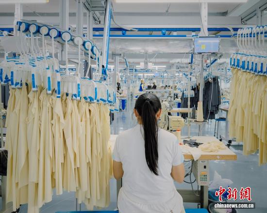 图为10月14日，贵州省都匀市绿茵湖轻纺产业园一家制衣厂生产车间内，工人在智能吊挂制衣生产线作业。