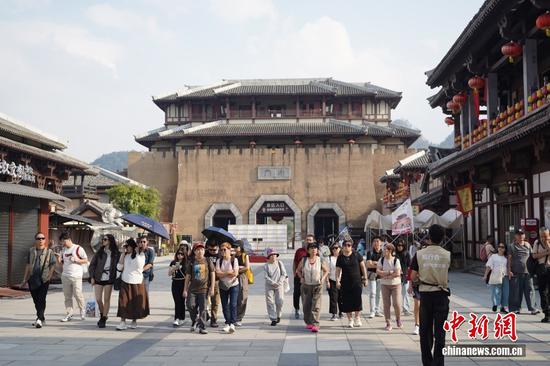 图为10月14日，都匀秦汉影视城吸引马来西亚游客游园打卡，沉浸式感受秦汉古韵。据悉，该影视城占地面积694亩，由6个区域230栋建筑组成，多部影视剧曾在此取景拍摄。