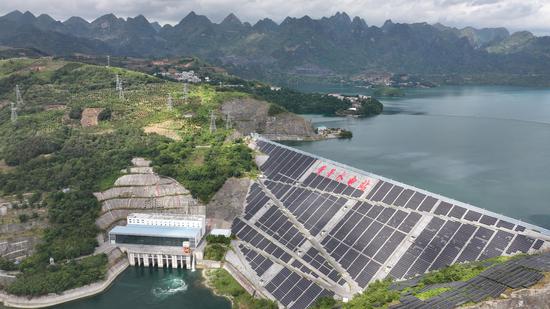 北盘江董箐水电站大坝横锁江面，坝面及两岸山脊上的连片光伏板在阳光下熠熠生辉。南方电网贵州电网公司通过水光“打捆”联合送出模式，将电平稳并入贵州电网。龙定锦 摄
