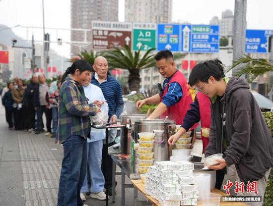 2026年4月以来，在贵州省贵阳市一家医院的后门，“80后”翟饶和熊泽珲每周一至周五免费为重病患者及家属送午餐和牛奶、鸡蛋。两人还在医院附近租下一间20多平方米的房屋作为“爱心厨房”，每天花3个多小时准备100余份餐食，菜单尽量变换花样，有冬瓜排骨、洋葱炒肉、西红柿炒鸡蛋等，每日配一荤汤和一素菜，他们希望尽自己所能，为癌症等重病患者及家属提供一些帮助。打饭时，他们常与患者及家属交流，鼓励大家积极战胜疾病。随着爱心不断传递，目前每天都有志愿者及患者家属前来帮忙做饭、送餐，也有爱心人士送来米、油、牛奶、鸡蛋等物资。图为10月27日翟饶（右三）和志愿者及大学生一起为重病患者及家属免费送午餐。中新社记者 周燕玲 摄
