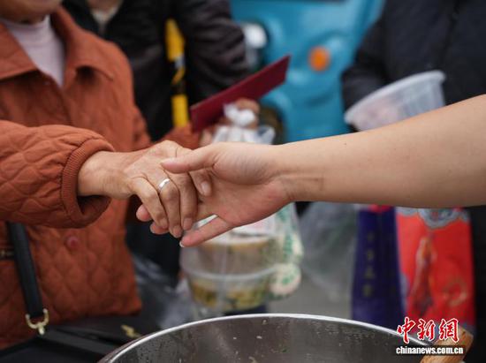 图为10月27日一位领到免费午餐的病患家属与志愿者握手。中新社记者 周燕玲 摄