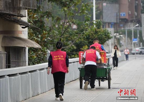 图为10月27日志愿者（后）帮助翟饶和熊泽珲送餐结束后，返回“爱心厨房”。中新社记者 周燕玲 摄