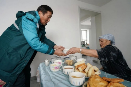 在新疆阿勒泰牧区，一位牧民倒奶茶招待上门的邮递员 来源：新华社e