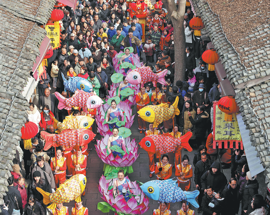&nbsp;Performers carrying intricate fish lanterns and showcasing lotus ships parade through the streets of the Langzhong ancient town in Sichuan province on Monday. The performance depicts koi fish swimming in waters, which symbolizes prosperity and abundance. Zhang Lang/China News Service