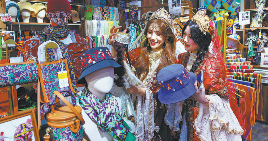 Tourists buy souvenirs at a shop near a scenic spot in Xinjiang. Photo/CHINA DAILY