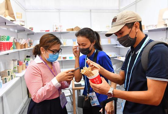 An exhibitor (left) talks over environmentally-friendly straws with Kazakh buyers during the 130th session of the China Import and Export Fair, also known as the Canton Fair in Guangzhou, South China's Guangdong province, Oct 15, 2021. (Photo: Xinhua)