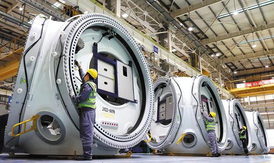 Workers assemble wind turbine wheels at a factory in Lianyungang Economic and Technological Development Zone, East China's Jiangsu province, Feb. 28, 2023. (Photo by Geng Yuhe/for China Daily)