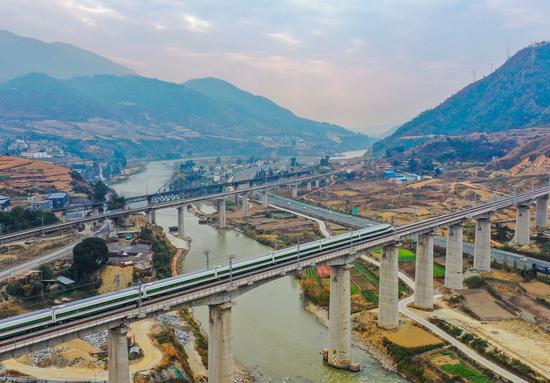 This aerial photo taken on Dec. 24, 2022 shows a Fuxing high-speed train making a trial run before the opening of the new Chengdu-Kunming Railway in Mianning County, southwest China's Sichuan Province. (Xinhua/Wang Xi)