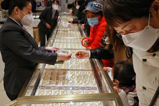 Shoppers look at gold ornaments at a jewelry store in Beijing. (PHOTO by JIANG DONG/CHINA DAILY)
