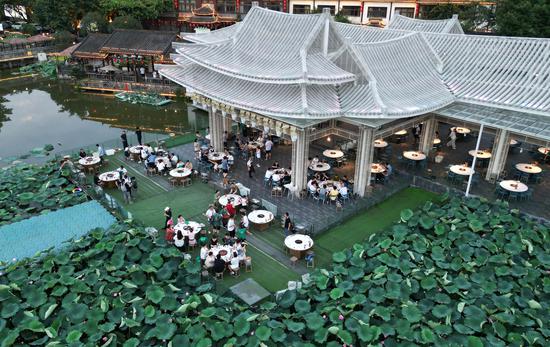 People enjoy hotpot beside lotus pond in Chongqing