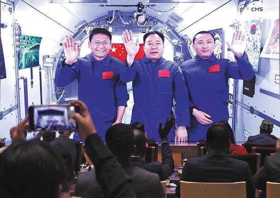 Chinese astronauts Jing Haipeng (center), Zhu Yangzhu (right) and Gui Haichao introduce 10 award-winning paintings, created by African youths, to an audience in Beijing via video link on Wednesday from the Tiangong space station. (Zou Hong/China Daily)