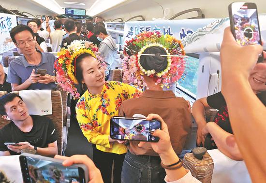 A passenger boards a Fuzhou-Xiamen high-speed railway train on Thursday, wearing floral headwear for an intangible cultural heritage promotional event. Wearing floral headwear is a custom of women from Xunpu, a fishing village in Quanzhou, Fujian province. Thursday was the first day of the high-speed railway's operations. (Photo/China Daily)