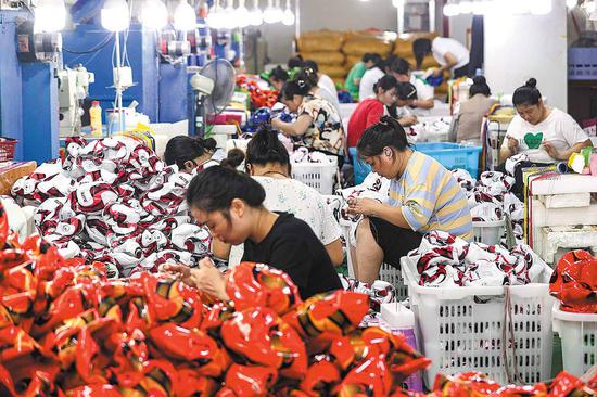 Workers are busy making soccer balls to fulfill overseas orders at a factory of a sports gear manufacturer in an industrial park in Zunyi, Guizhou province, on Tuesday. (QU HONGLUN/CHINA NEWS SERVICE)
