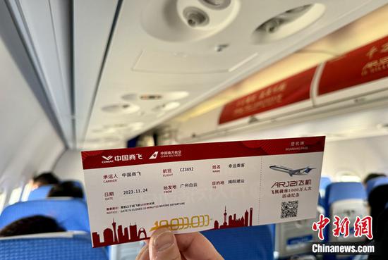 A passenger holds a boarding pass in the ARJ21 jet, Nov. 24, 2023. A commemorative boarding pass and other gifts were prepared for each passenger of the ARJ21, which has served more than 10 million passengers. (Photo: China News Service/ Sun Zifa)