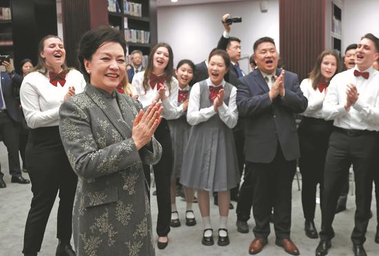 Peng Liyuan, wife of President Xi Jinping, interacts with the visiting members of Burg Chinese Chorus from Essen, Germany, on Thursday at Beijing No 35 High School. (Wang Jing/China Daily)