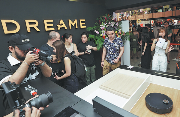 People take photos of a robot vacuum cleaner on the opening day of Dreame's flagship store in Singapore on Jan 3. CHINA DAILY