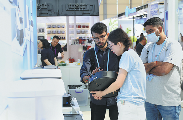 Customers learn about Chinese robot vacuums at the Canton Fair in Guangzhou, Guangdong, on April 16. (LU HANXIN/XINHUA)