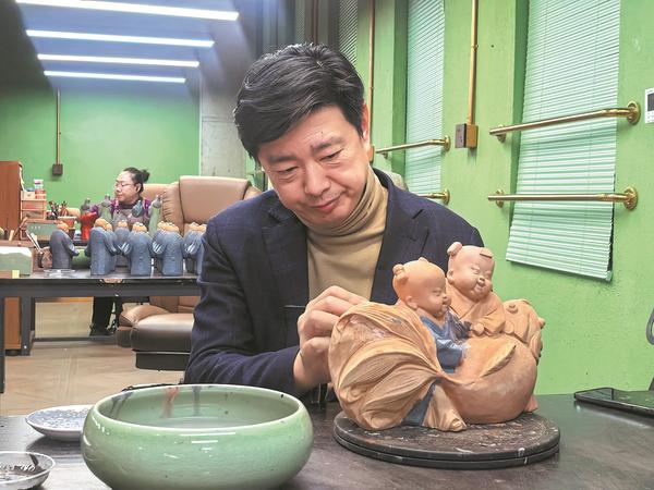 Zhang Yu refines a Spring Festival-themed sculpture in February. (Photo provided to China Daily)