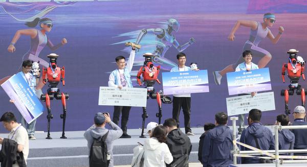 Robots "Lightning" from champion team Qitian Dasheng (C), runner-up team Leiting Flash (2nd L) and third-place team Xinghuo Liaoyuan (1st R) stand on the podium during the award ceremony of the Beijing humanoid robot half marathon, on April 19, 2026. (Photo by Zou Hong/chinadaily.com.cn)