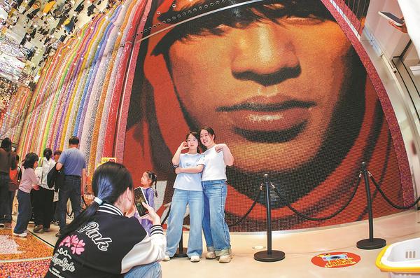 Customers take photos in front of a giant cover of Jay Chou's Fantasy album made of lollipops at Snack Kingdom, the world's largest snack store, which opened in Changsha, Hunan province, on Friday. （Photo provided to China Daily）
