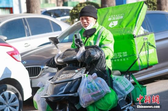12月17日，一名外卖员配送途中查看订单。近日，受疫情影响，北京多区外卖企业订单配送压力较大。   中新社记者 贾天勇 摄