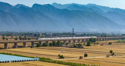 High-speed train travels through golden wheat fields at the foot of Mount Hua in Huayin, Shaanxi