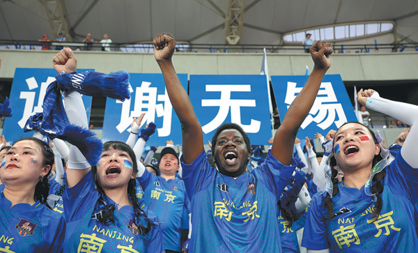 A foreign spectator watches a match alongside Chinese fans during a "Suchao" game in Jiangyin, Jiangsu province, on May 30. The host, Wuxi team, played out a 0-0 draw against the Nanjing team. WAN CHENGPENG/FOR CHINA DAILY