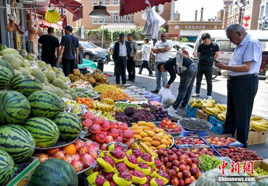People buy fruit at roadside stalls in Urumqi, Xinjiang Uygur Autonomous Region June 6. (Photo/China News Service)