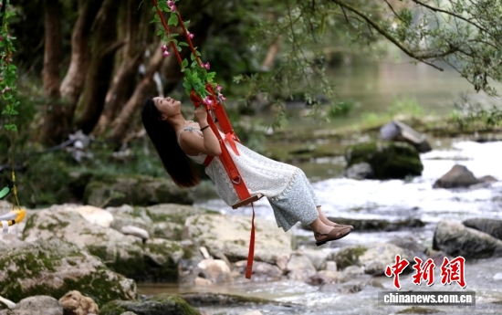 A visitor enjoys the cool breeze on a swing in Enshi, Hubei province on May 26, 2026. (Photo: China News Service)