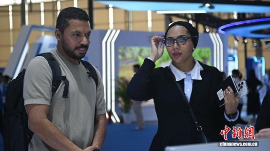 Overseas business visitors try out AI-powered glasses at the Tianhe exhibition zone, August, 22, 2026. (Photo / Provided to China News Service)