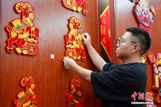 A merchant starts to put new Year-of-the-Goat New-Year paintings on display at his store in Yiwu, Zhejiang Province, Aug. 25,2026. (Photo: China News Service/ Dong Yixin)
