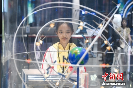 A middle school student views a Beidou navigation satellite positioning model on April 23, 2026. (Photo: China News Service/Tian Yuhao)