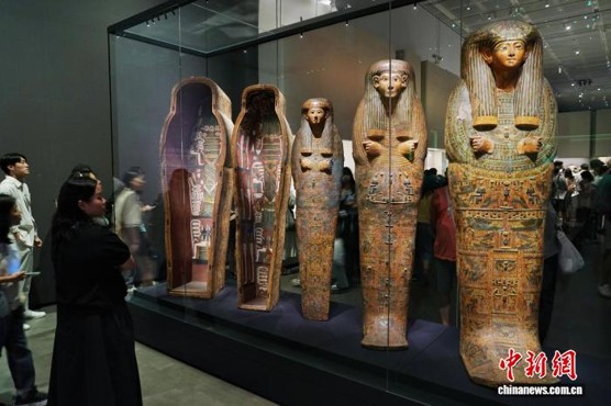 Visitors view anthropoid coffins at the exhibition. (Photo: China News Service/ Zhang Xiangyi)