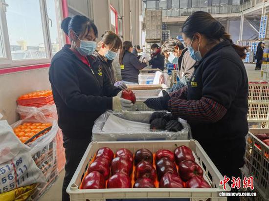 Workers pack apples in a factory in Tianshui, Gansu Province. (Photo: China News Service/Liu Yutao)
