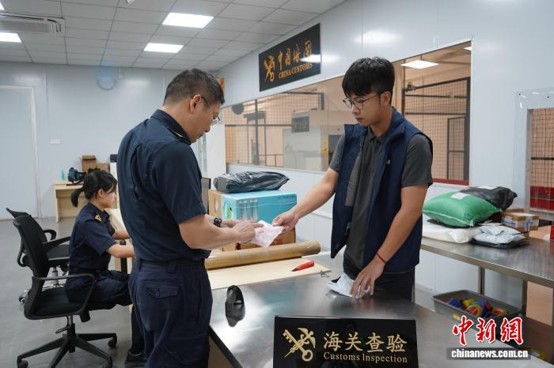 Customs officers of Hengqin Customs inspect cross-border e-commerce parcels. (Photo: China News Service/ Yang Jing)