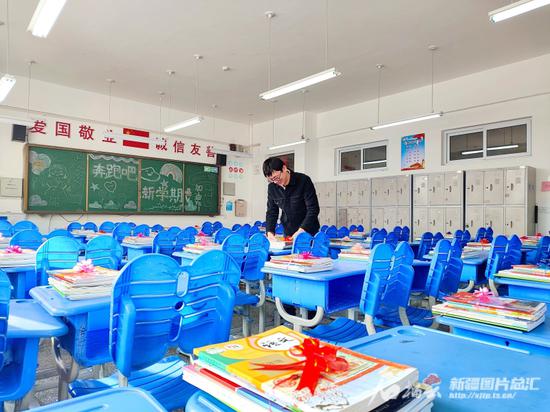 2月22日,乌鲁木齐市第127中学教师将崭新的书本分发到每名学生的座位