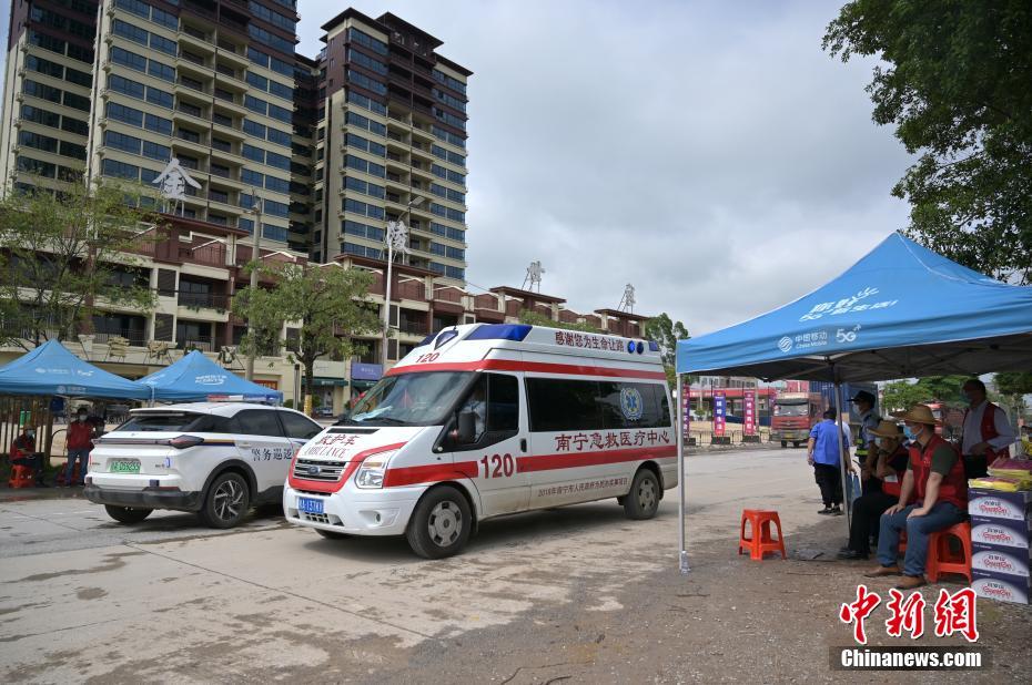 5月25日,广西南宁市金陵镇一街道旁设置防疫检查点,一辆救护车从金陵