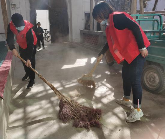 志愿者正在帮助居民打扫庭院(李蓉摄)