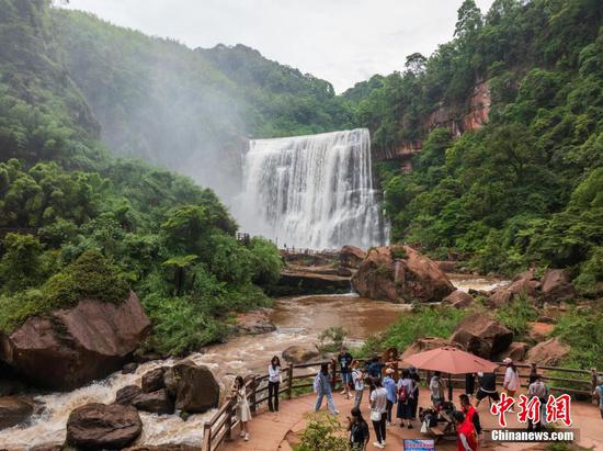 5月27日,游客在赤水丹霞旅游区·赤水大瀑布前游玩拍照