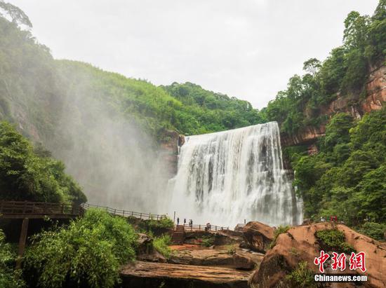 5月27日,游客在赤水丹霞旅游区·赤水大瀑布前拍照打卡