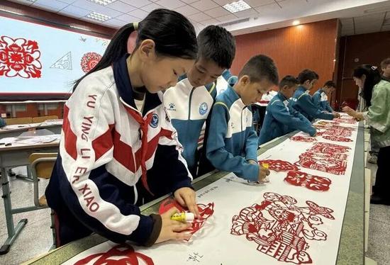 和田“足球小巴郎”在天津市河北区育婴里第二小学学习剪纸技艺。李凌燕 摄